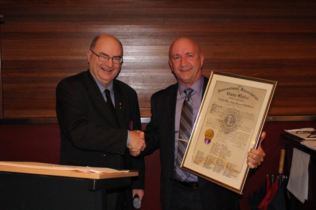 Outgoing Club President, Tony Pederick OAM, passing over the Club Charter to Incoming President, Lindsay Miller.